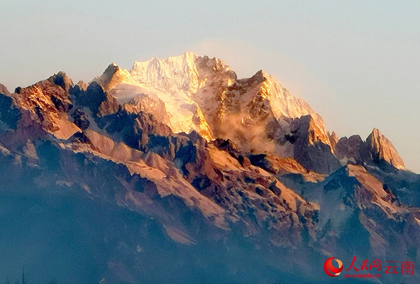 Снежная гора Юйлун в солнечных лучах отливает золотом